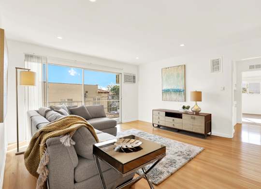 A modern living room with a grey sofa and a coffee table at Wooster Encore Apartments, Los Angeles, California