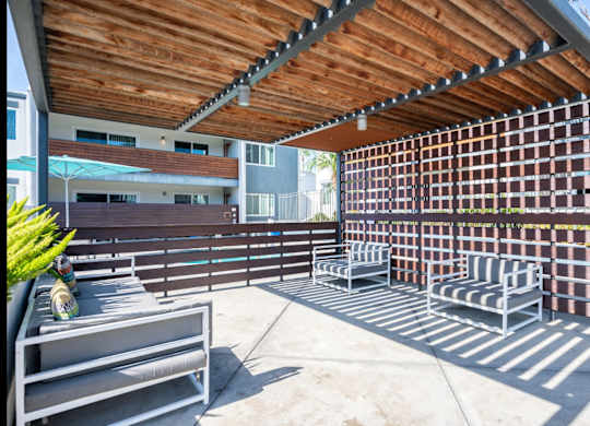 A patio with a wooden ceiling and a metal bench.