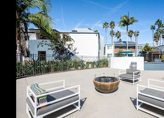 A patio with white furniture and a fire pit.