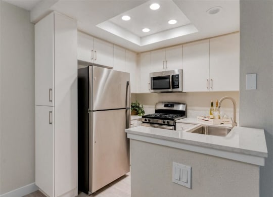 a kitchen with a refrigerator freezer next to a stove top oven  at Laguna Gardens Apts., California