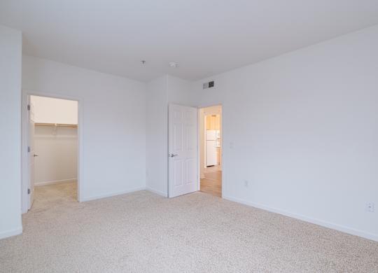 A large, empty room with white walls and carpeted floor at Cornerstone at Gale Ranch Apartments, San Ramon