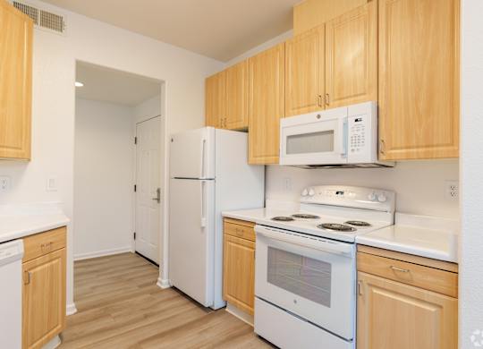 A kitchen with white appliances and wooden cabinets at Cornerstone at Gale Ranch Apartments, California