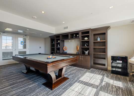 A room with a pool table and a cabinet with glass doors at Deer Creek Senior Apartments in San Ramon, CA 94582