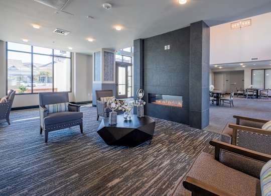 Lobby with a fireplace and a dining area in the background at Deer Creek Senior Apartments in San Ramon, CA 94582