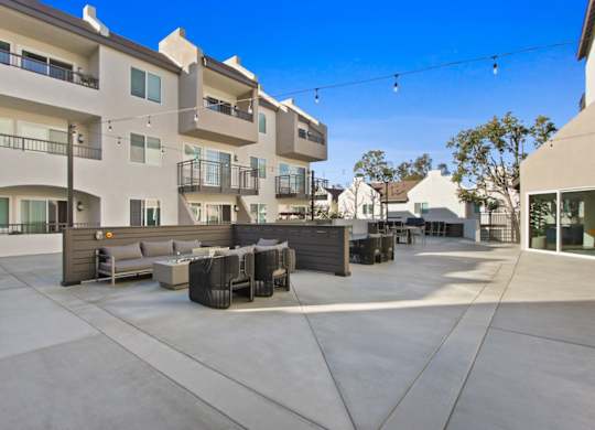 A sunny day at a modern apartment complex with a patio area.