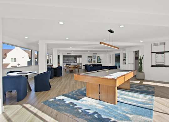 A modern living room with a blue rug and a wooden coffee table.