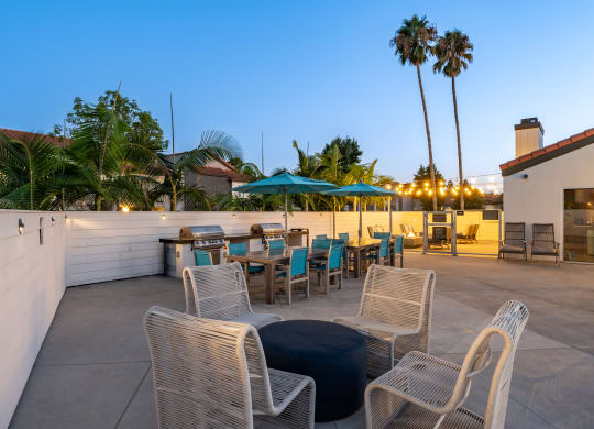 a rooftop patio with tables and chairs and palm trees at Laguna Gardens Apts., Laguna Niguel, California