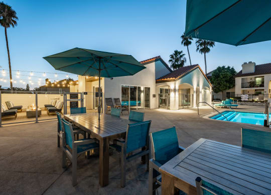 a dining table with chairs and umbrellas next to a pool  at Laguna Gardens Apts., California, 92677