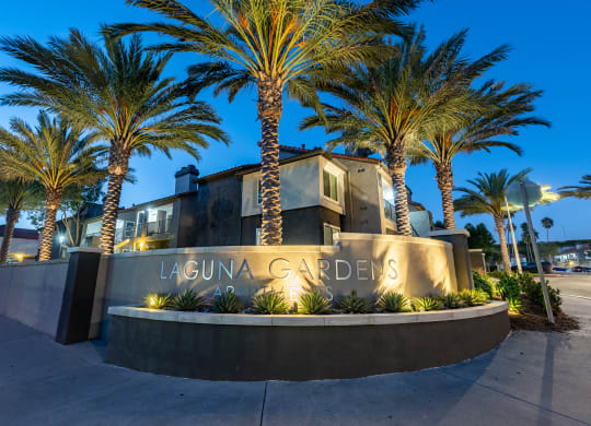 a sign in front of a building with palm trees  at Laguna Gardens Apts., Laguna Niguel
