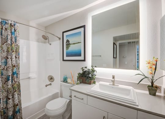 a bathroom with a white toilet next to a white bathtub and a white sink with a  at Laguna Gardens Apts., Laguna Niguel, CA