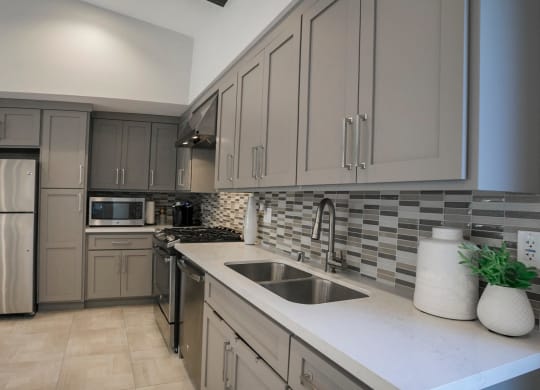 a kitchen with gray cabinets and a white counter top  at Arroyo Villa Apartments, Thousand Oaks, California