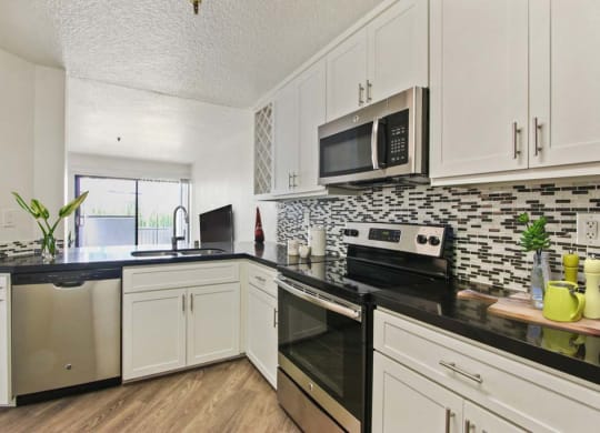 a kitchen with white cabinets and black counter tops  at Masselin Park West, Los Angeles, CA