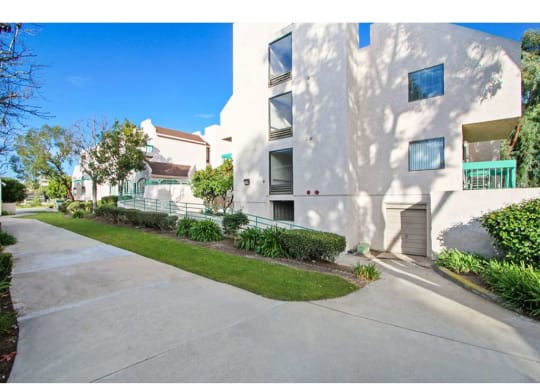 a white apartment building with a sidewalk in front of it  at Harvard Manor, Irvine, 92612