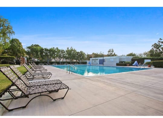 a swimming pool with chaise lounges and trees in the background  at Harvard Manor, Irvine, California