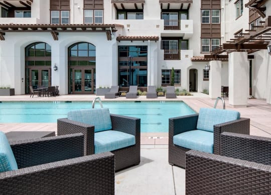 a swimming pool with blue chairs in front of a building  at Deer Creek Apartments, San Ramon, 94582