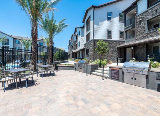 a patio with tables and chairs and a grill at The Vineyards Apartments, Porter Ranch, CA