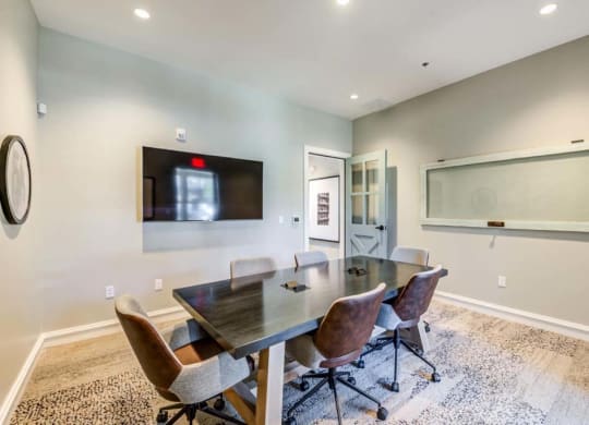 a conference room with a table and chairs and a tv on the wall  at The Vineyards Apartments, California