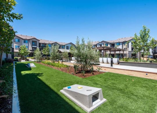 a grassy area with a fountain and apartment buildings in the background  at The Vineyards Apartments, California