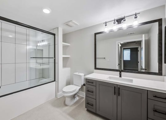 a bathroom with a toilet sink mirror and shower at The Vineyards Apartments, Porter Ranch, CA, 91326