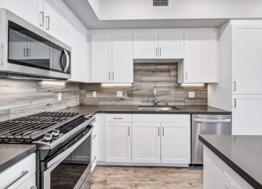 a kitchen with a stove top oven next to a sink at The Vineyards Apartments, Porter Ranch, CA, 91326