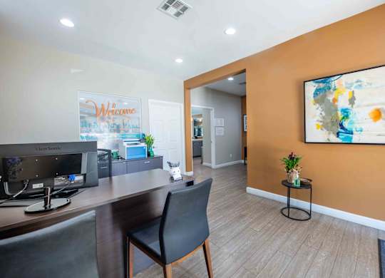 A room with a desk, chair, and a painting on the wall.