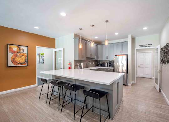 A kitchen with a white countertop and bar stools.