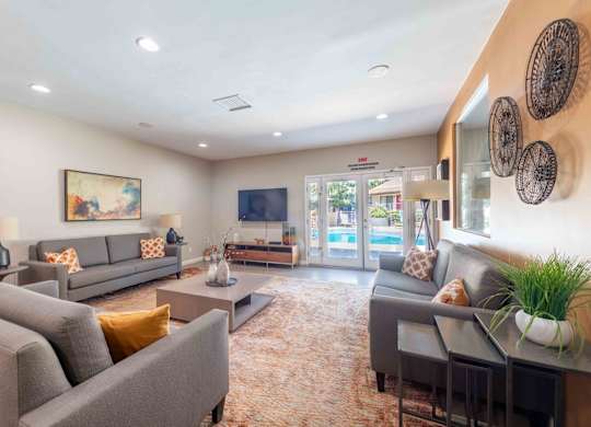 A living room with grey couches and a painting on the wall.