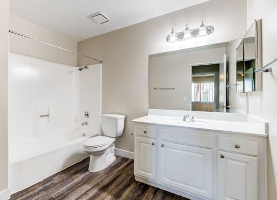 a bathroom with a toilet sink mirror and bathtub  at Redlands Park Apts, Redlands, 92373