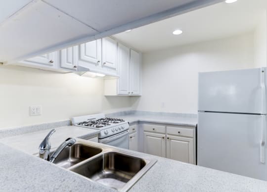a kitchen with white cabinets and white appliances  at Redlands Park Apts, Redlands