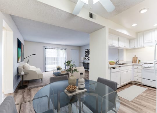 a living room with a glass table and a kitchen in the background at Redlands Park Apts, Redlands, CA