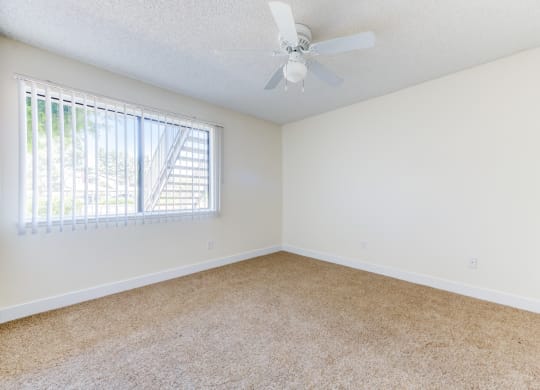 a bedroom with a ceiling fan and a window  at Redlands Park Apts, Redlands, CA, 92373