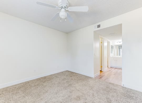 a bedroom with white walls and a ceiling fan  at Redlands Park Apts, Redlands, CA
