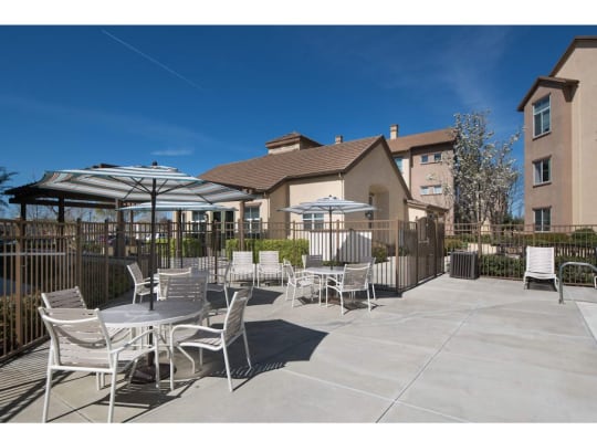 a patio with tables and umbrellas and a building in the background  at Seville at Gale Ranch, California