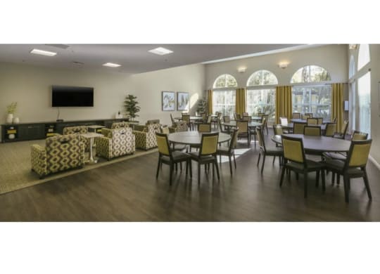 a large room with tables and chairs and a flat screen tv  at Tesoro Senior Apartments, Porter Ranch, CA