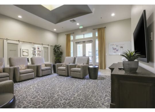 a room with couches and chairs and a tv on the wall  at Tesoro Senior Apartments, Porter Ranch