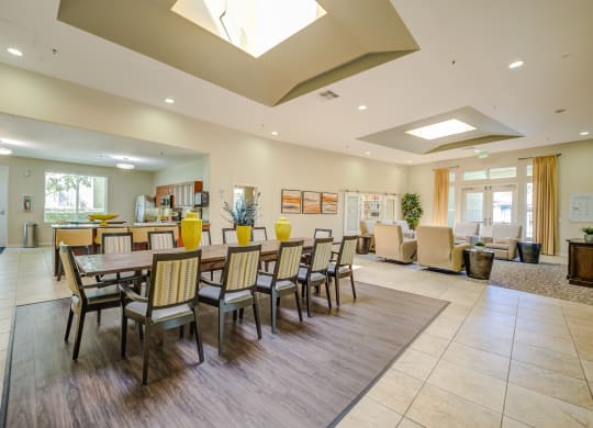 a resident clubhouse with a long table with chairs and a kitchenette in the background  at Tesoro Senior Apartments, Porter Ranch, CA, 91326
