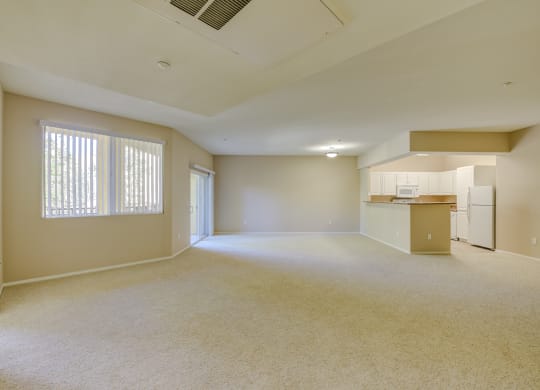 an empty living room with a kitchen in the background  at Tesoro Senior Apartments, Porter Ranch, CA