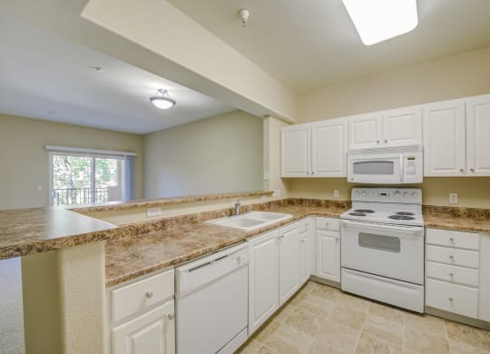 a kitchen with white cabinets and white appliances  at Tesoro Senior Apartments, Porter Ranch, CA, 91326