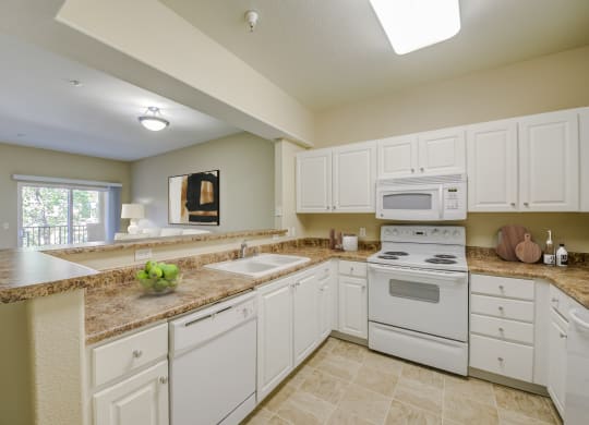 a kitchen with white cabinets and white appliances  at Tesoro Senior Apartments, Porter Ranch, CA
