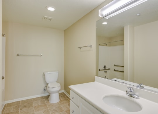 a bathroom with a sink toilet and mirror  at Tesoro Senior Apartments, California