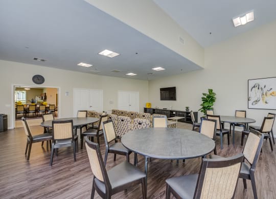 a resident clubhouse with tables and chairs and a flat screen tv  at Tesoro Senior Apartments, Porter Ranch, CA