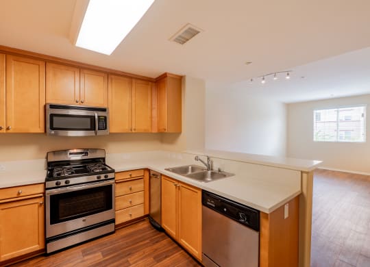 a kitchen with wooden cabinets and stainless steel appliances  at Ventana Senior Apartments, Northridge, California