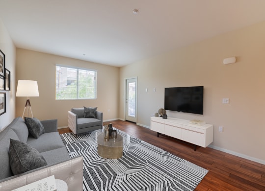 a living room with a couch and chair and a tv on the wall  at Ventana Senior Apartments, Northridge, CA, 91326