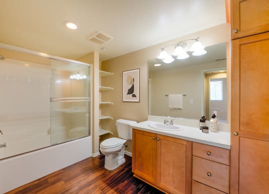 a bathroom with a toilet sink and shower  and mirror with vanity lights at Ventana Senior Apartments, Northridge, 91326