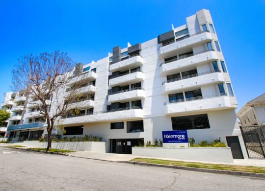 a white apartment building with a blue sign in front of it at The Kenmore Los Feliz, California