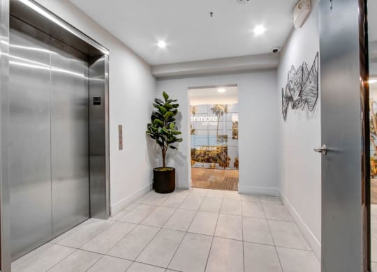 the entrance to a building with a metal elevator and a large plant in the corner at The Kenmore Los Feliz, Los Angeles, CA, 90027-4063