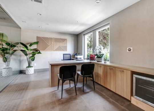 a home office with a wooden desk and two black chairs in front of a large window at Toluca Court, Toluca Lake, California