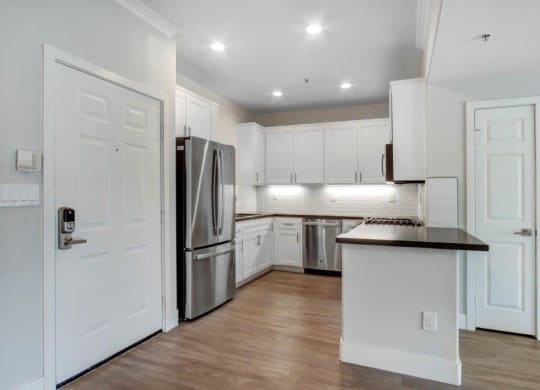 a kitchen with white cabinets and a stainless steel refrigerator at Toluca Court, Toluca Lake, CA