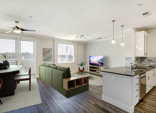 A modern kitchen with a green sofa and a dining table. at Apex Mission Valley, San Diego, CA, 92108