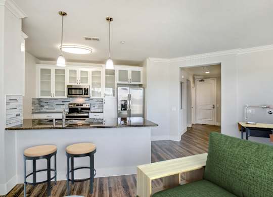 A kitchen with a bar area and a green couch. at Apex Mission Valley, San Diego